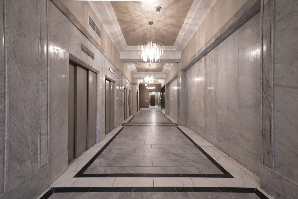 Upper floor elevator lobby with marble walls and floors.